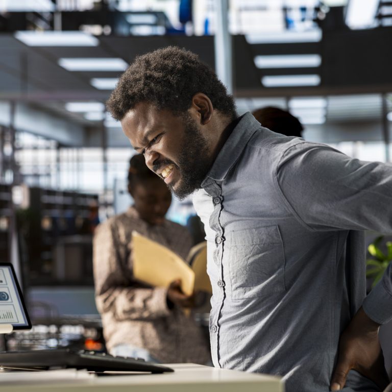 African american business analyst deals with back pain and muscle cramps, improving his incorrect posture at the desk. Suffering from spasms and inflammation due to sedentary life.